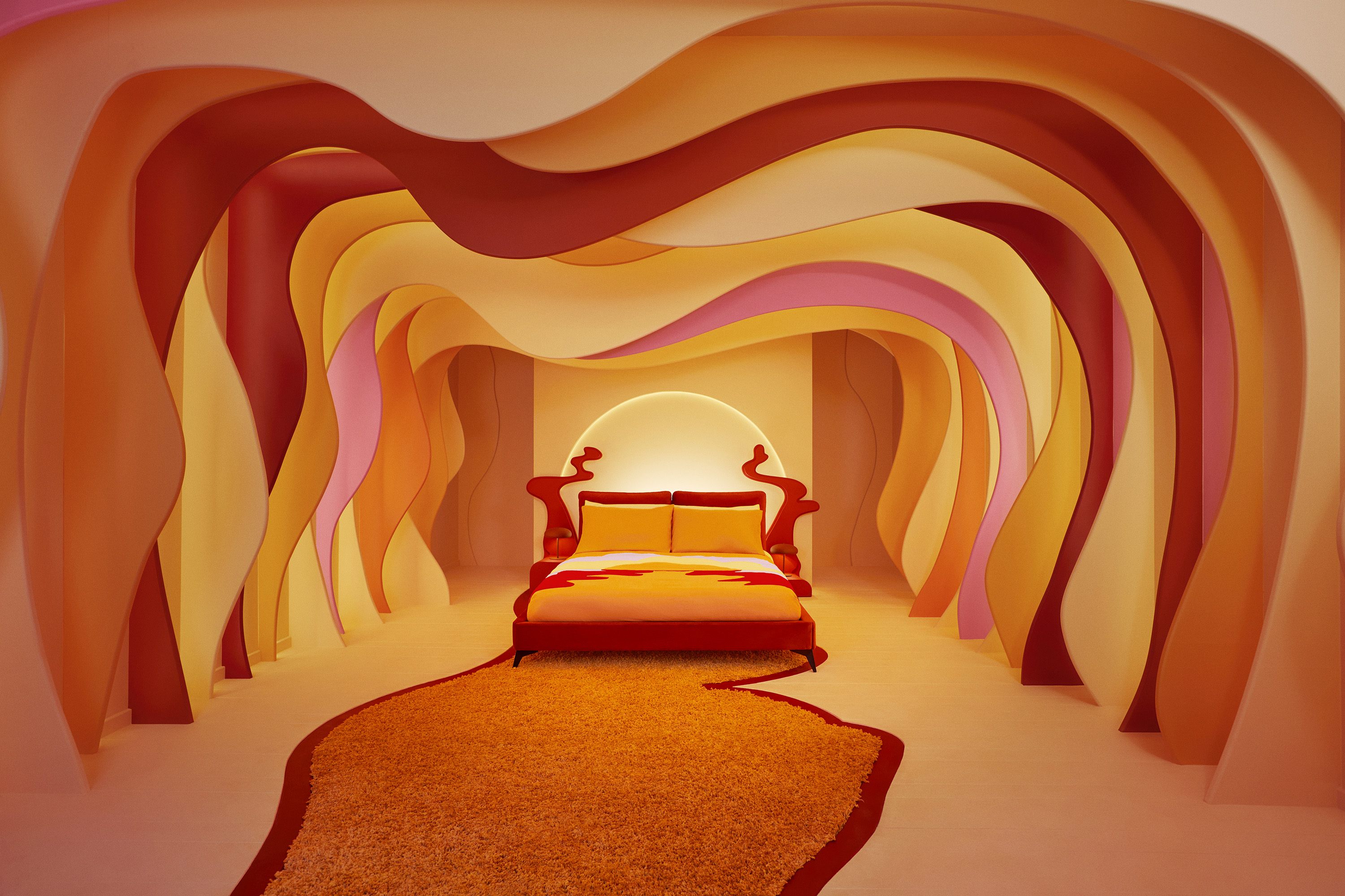 The sumptuous bed surrounded by red and orange waves that emulate the melting sunset colorways of the Sundown Cardigan. — Photo by Airbnb