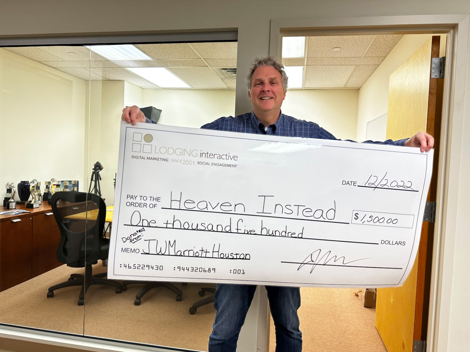 Lodging Interactive’s Founder & CEO holding the ceremonial check paid to Heaven Instead on behalf of the JW Marriott Houston Downtown Hotel. — Photo by Lodging Interactive